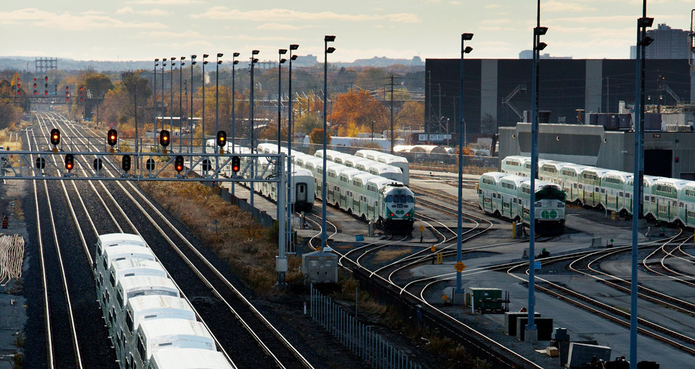 Commuter train equipment in yard with one train passing on main line