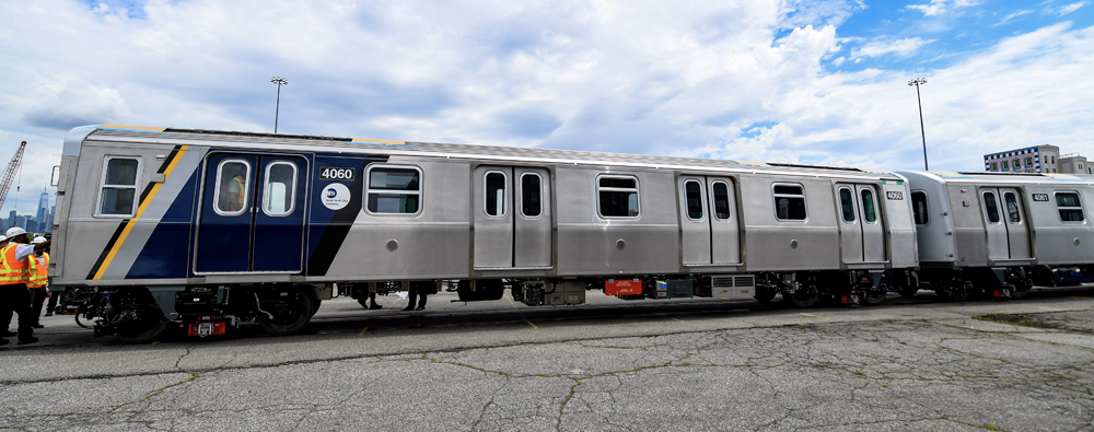 Side view of silver subway car with blue striping