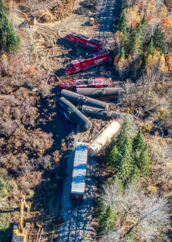 Three red locomotives and several freight cars perpedicular to track after derailing
