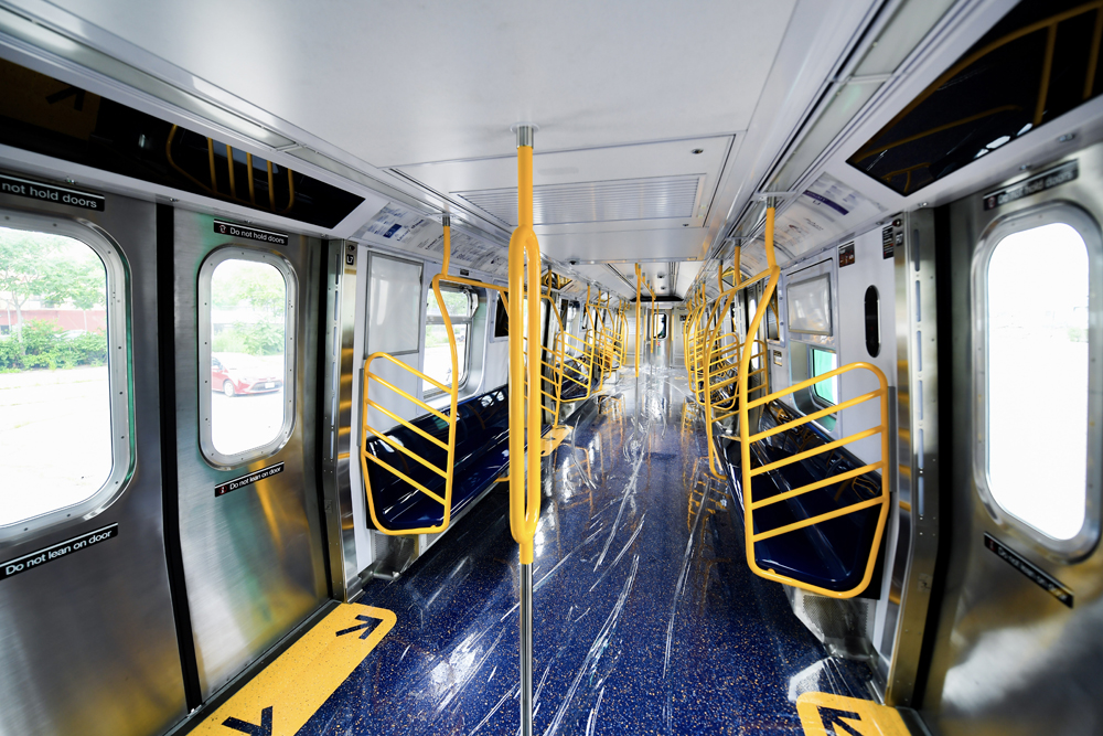 Inside of subway car with yellow railings and blue floor