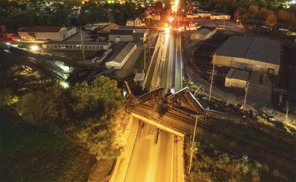 Nighttime aerial view of derailed tank cars on bridge