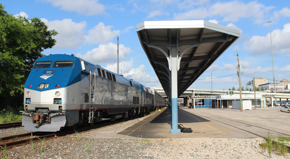 Passenger train stopped at station platform under blue skies