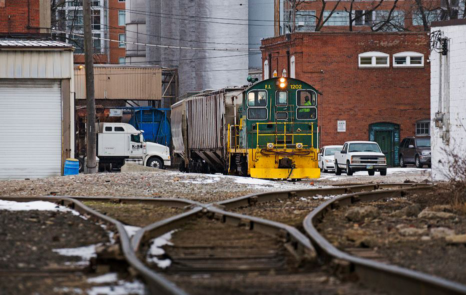 Switchers are resilient: Green end-cab switcher visible from distance inside industrial plant