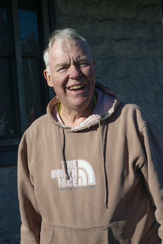 Smiling gray-haired man in tan hooded sweatshirt