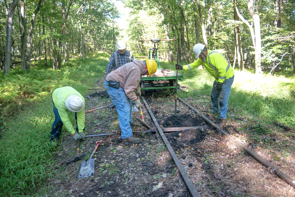 Four men working with hand tools on railroad track