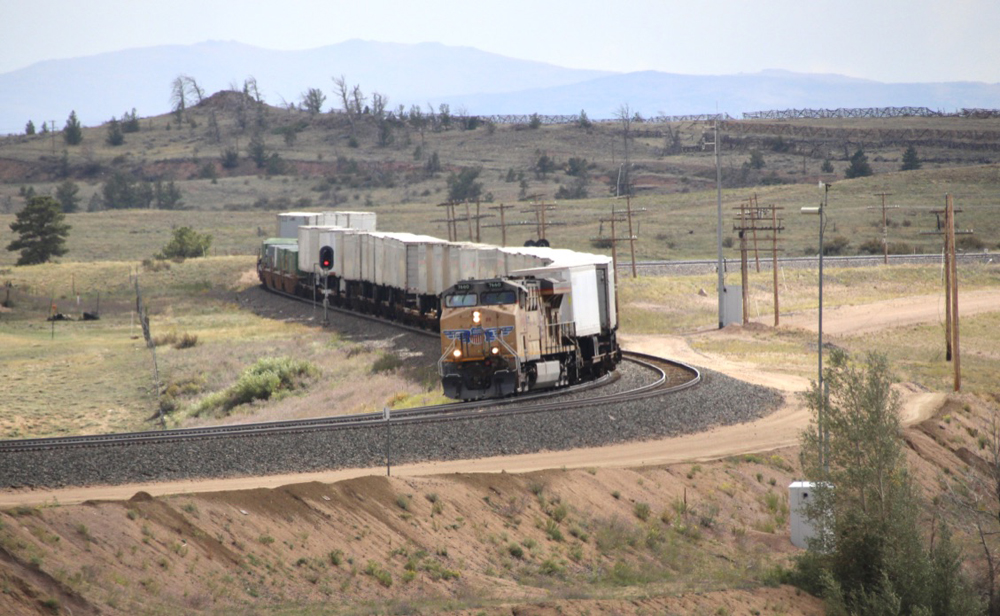 Yellow locomotive with train of trailers and containers