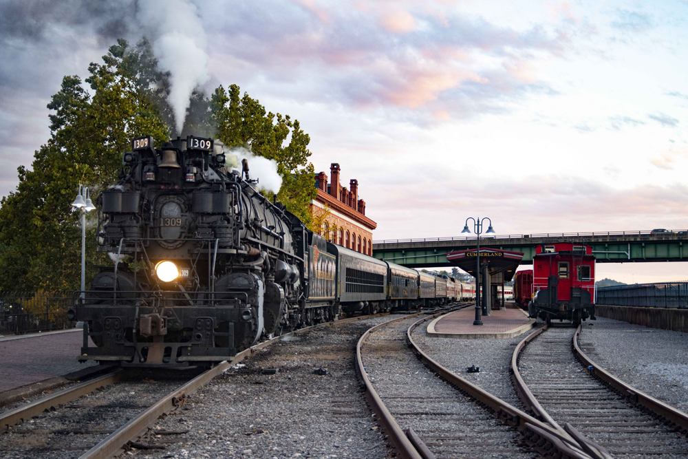 Large steam locomotive with passenger train on curve at dusk