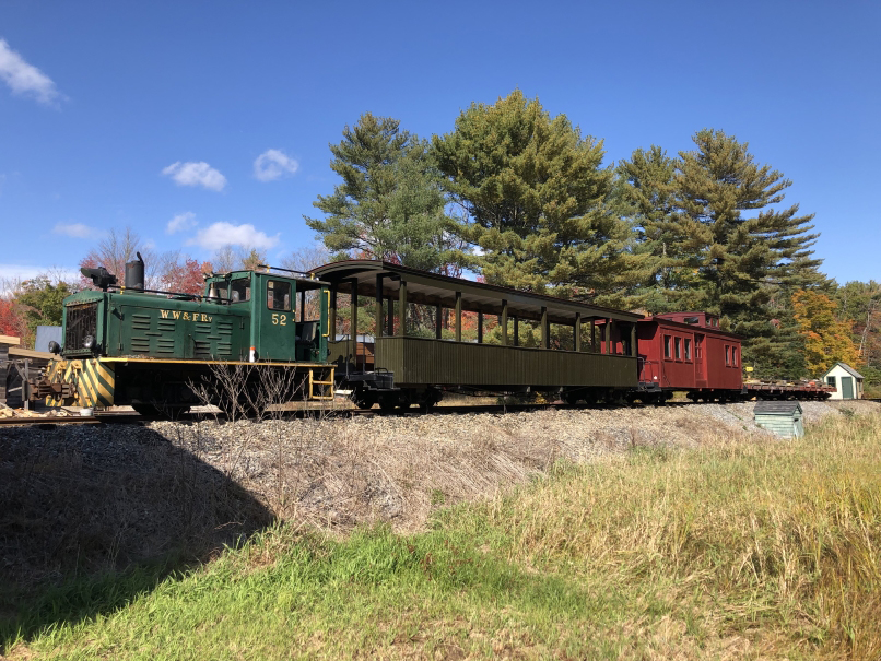 Small green diesel locomotive with open air passenger car and caboose