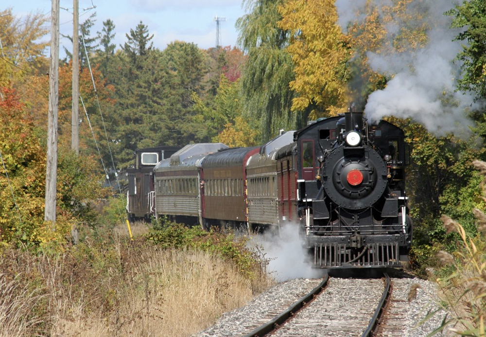 Steam locomotive rounds curve wth short passenger train