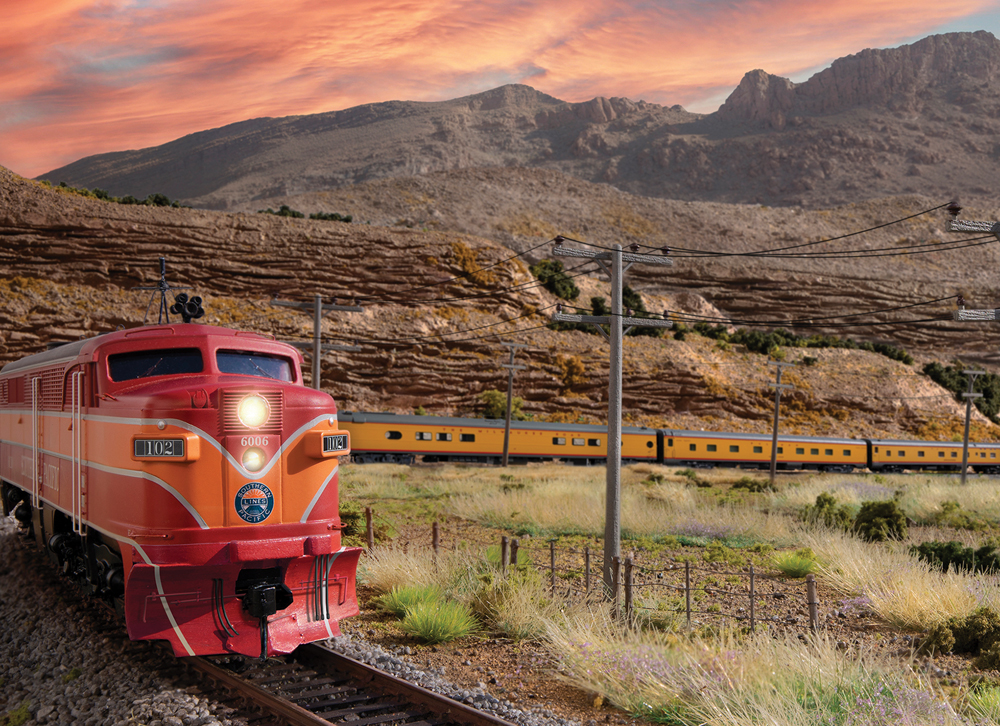 Model train passing mountainous terrain during a sunset