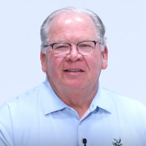 Man with glasses and gray hair in white shirt