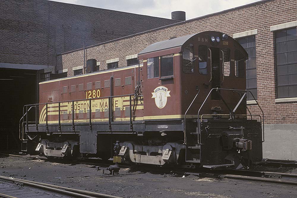 End cab Alco S5 locomotive outside brick building