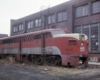 Red diesel Missouri-Kansas-Texas locomotive outside shop building
