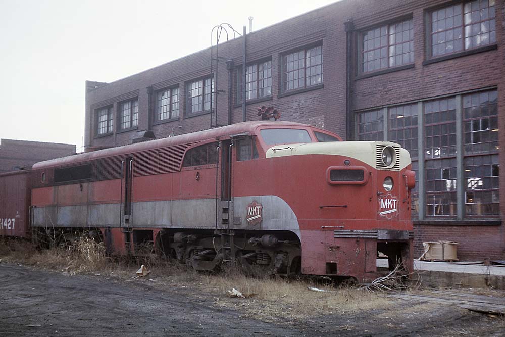 Red diesel Missouri-Kansas-Texas locomotive outside shop building