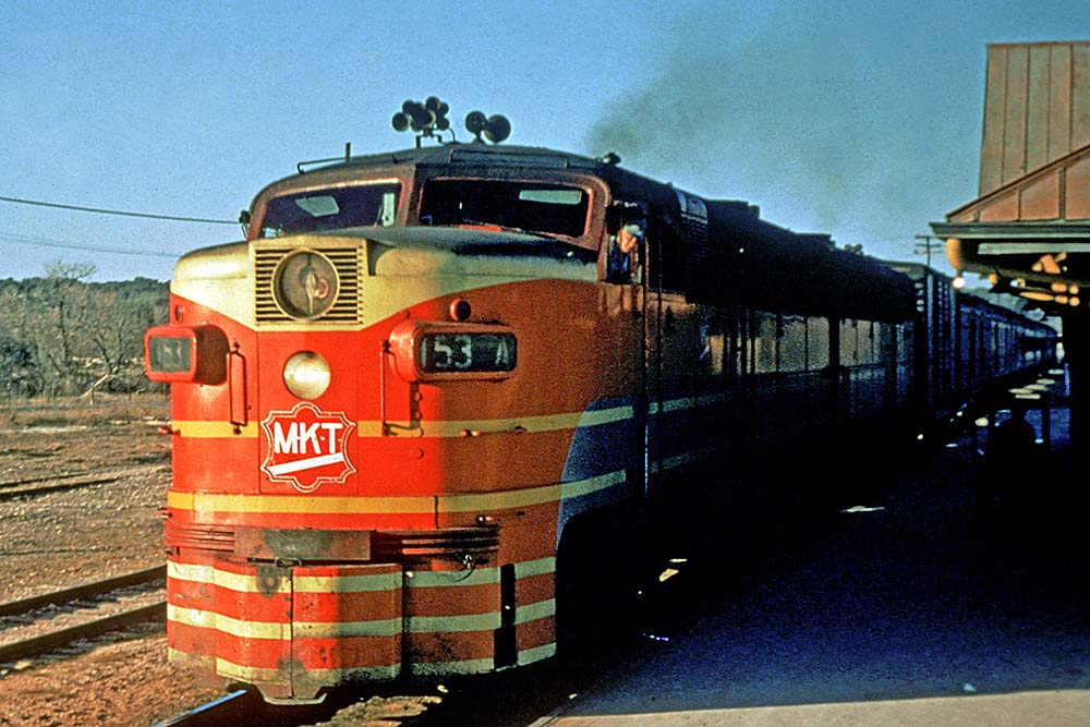 Red-and-yellow Missouri-Kansas-Texas Railroad diesel locomotive on passenger train in station