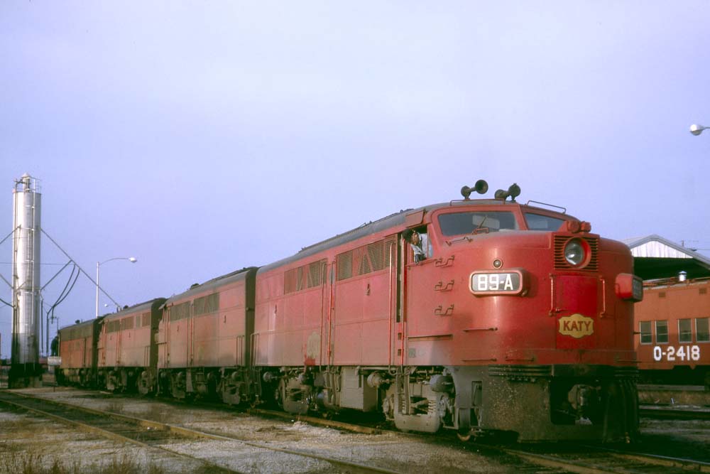 Red diesel Missouri-Kansas-Texas locomotives outside shop building