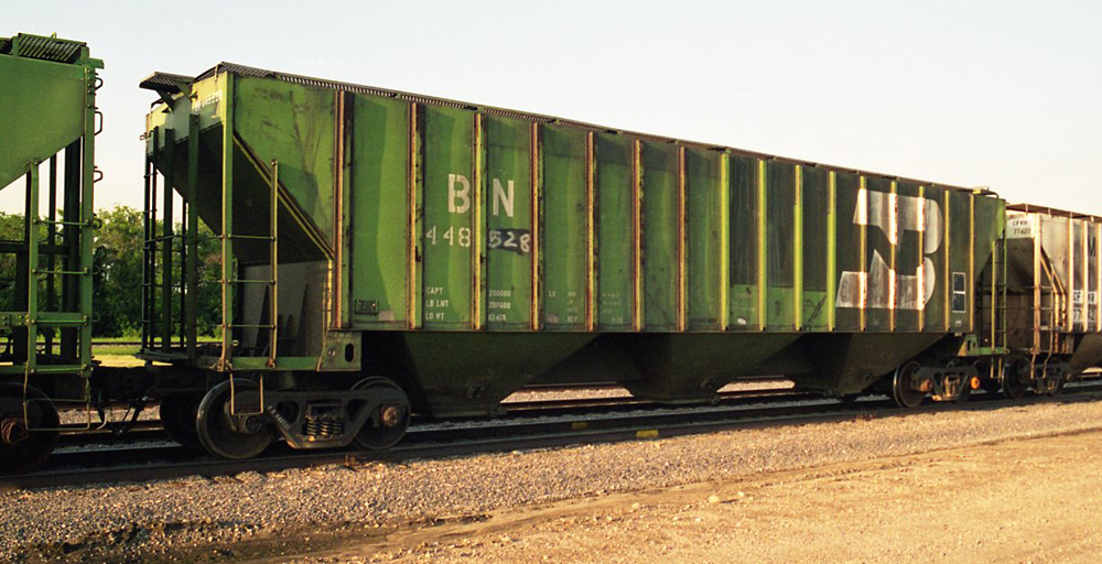 Photo of green freight car with other railroad cars in yard