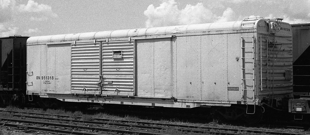 Black-and-white photo of boxcar in white paint with black lettering