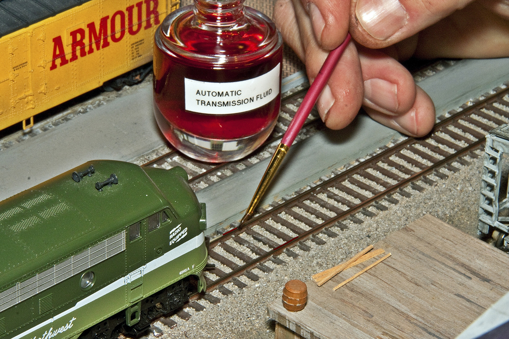 Photo of automatic transmission fluid being applied to HO scale track with a paintbrush