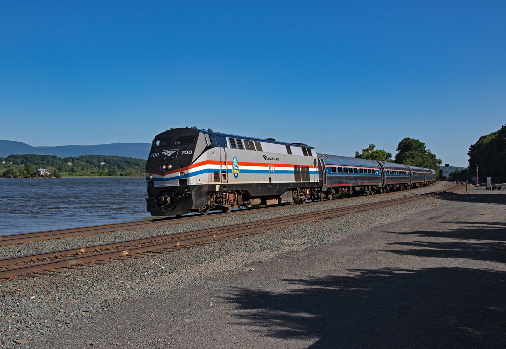 black and silver passenger train running along a river