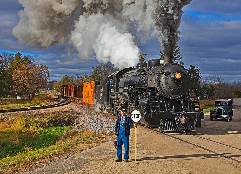 black steam locomotive in country with gray smoke coming from stack