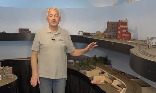 Man standing in front of a model train layout.