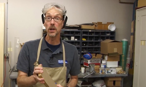 Man in workshop attire wearing surprised look.