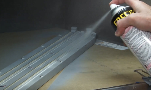 Hand holding spray paint can and painting in a paint booth.