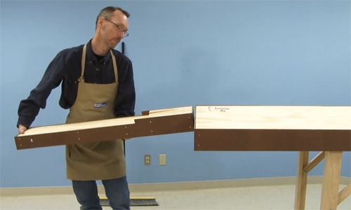 Man lifting a collapsable section onto a table.