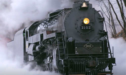 Black steam locomotive surrounded by a cloud of steam.