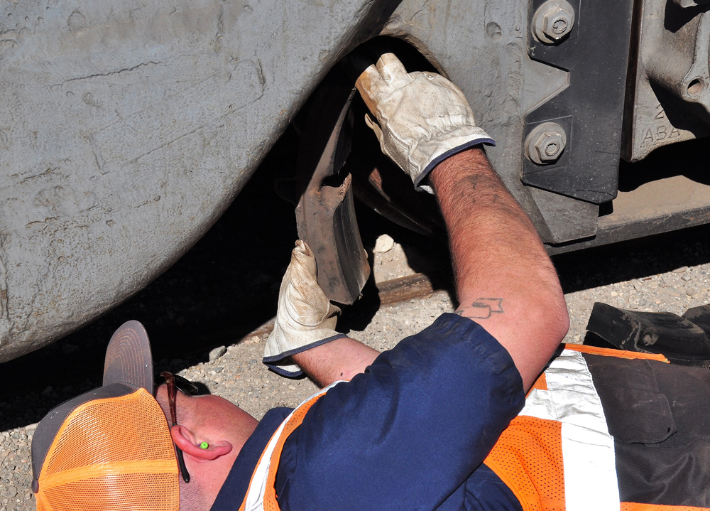 Man works underneath locomotive.