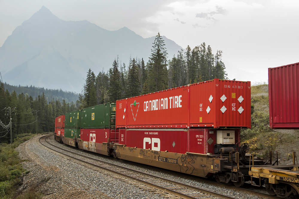 Red oversized container on train in mountains