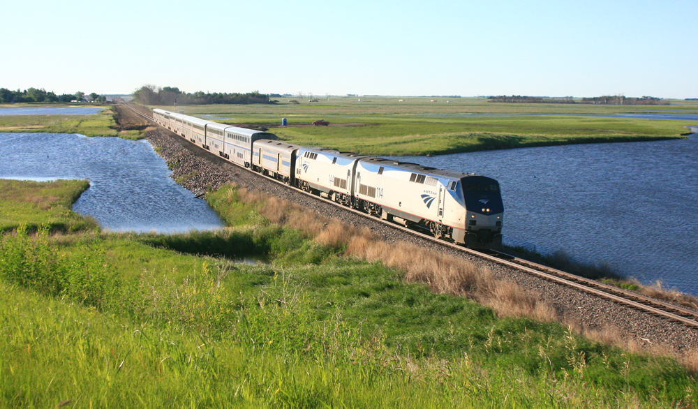Passenger train on embankment crossing lake