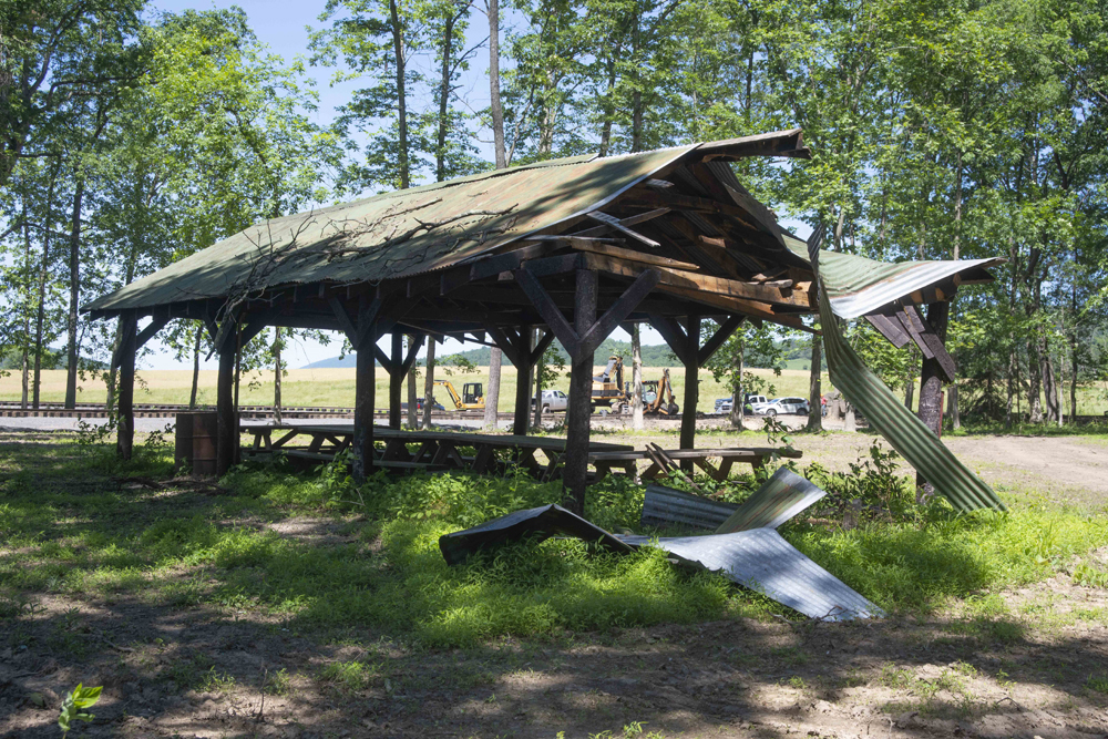 Badly damaged open-sided shelter over picnic tables