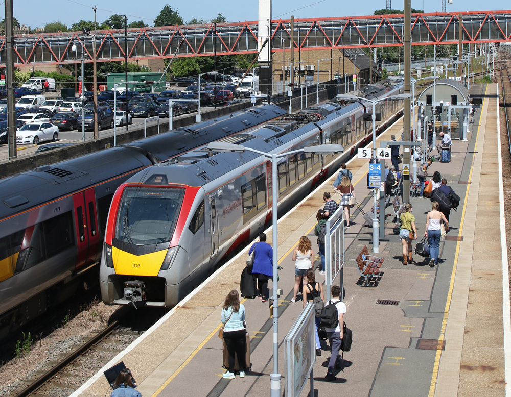 View from bridge of train arriving at station with passengers waiting on platform