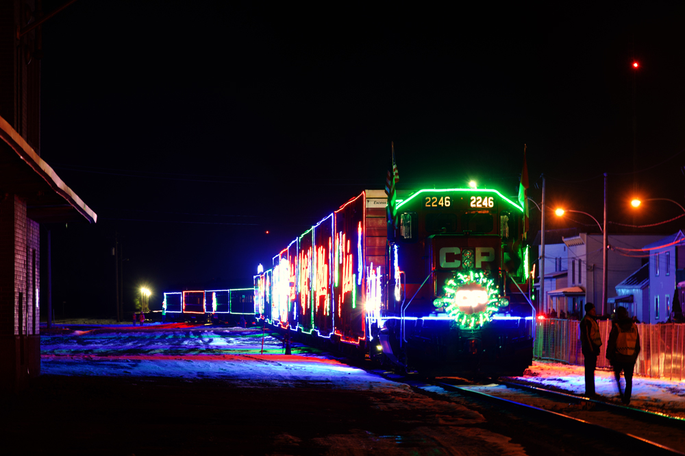 Train decorated with Christmas lights stopped near station at night