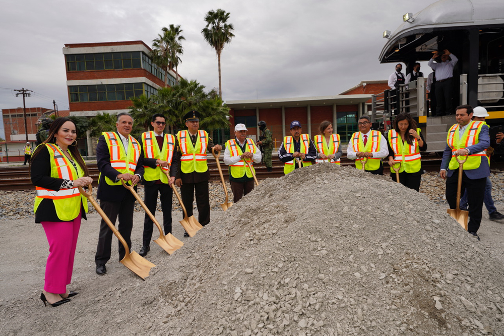 10 people posed with shovels around mound of dirt