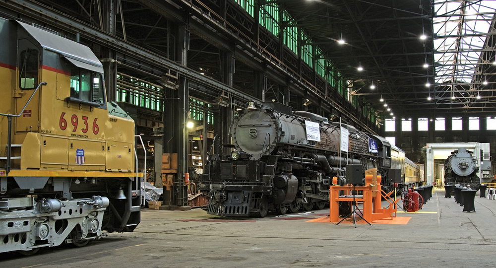Diesel and two steam locomotives in large shop building
