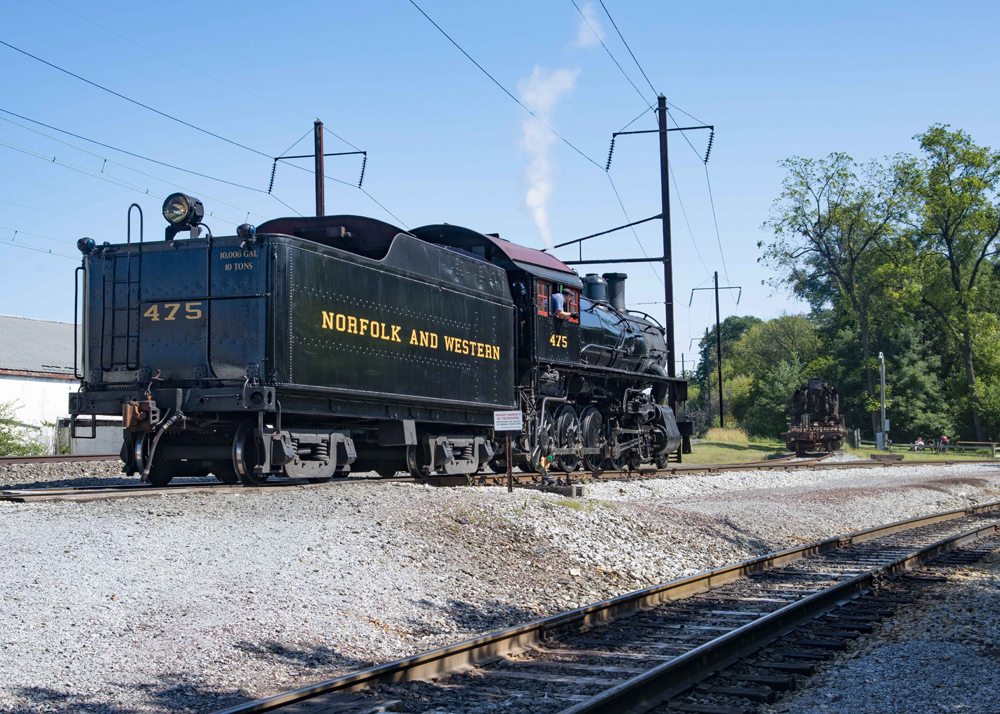 Steam locomotive passes siding with one piece of equipment