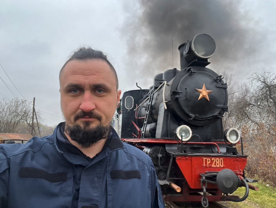 Man posing for selfie with steam locomotive