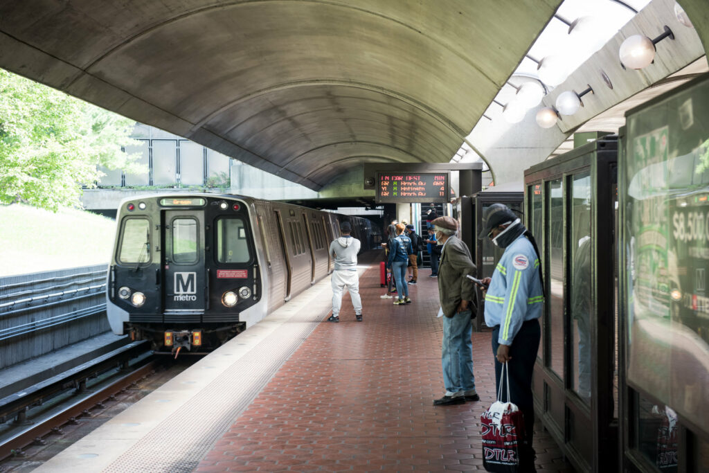 Rapid-transit train arrives in station as people wait on platform