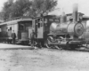 Men stand in front of steam locomotive and passenger car