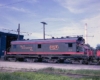 Green-and-red electric locomotive outside shop building