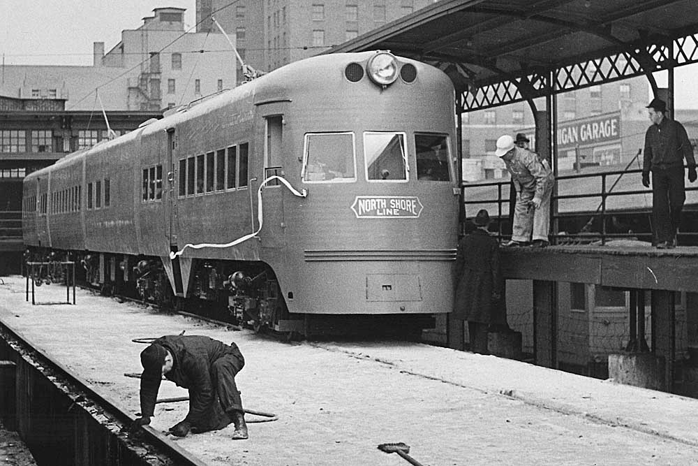 Men check station clearances by streamlined Chicago North Shore & Milwaukee equipment