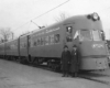 Two men stand in front of electric Chicago North Shore & Milwaukee equipment in street