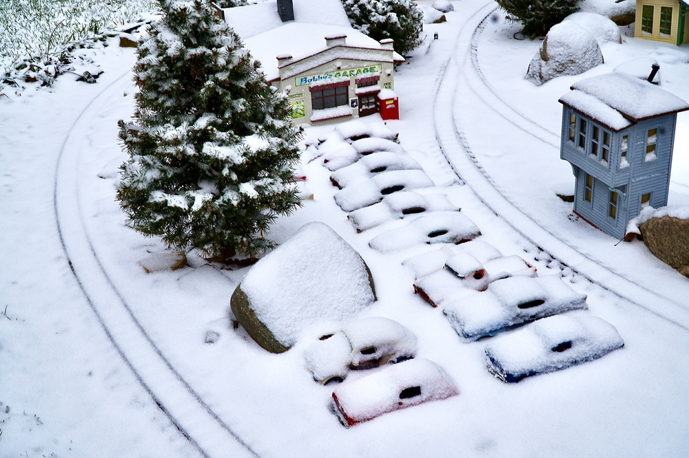 snowy scene of model auto garage on garden railway