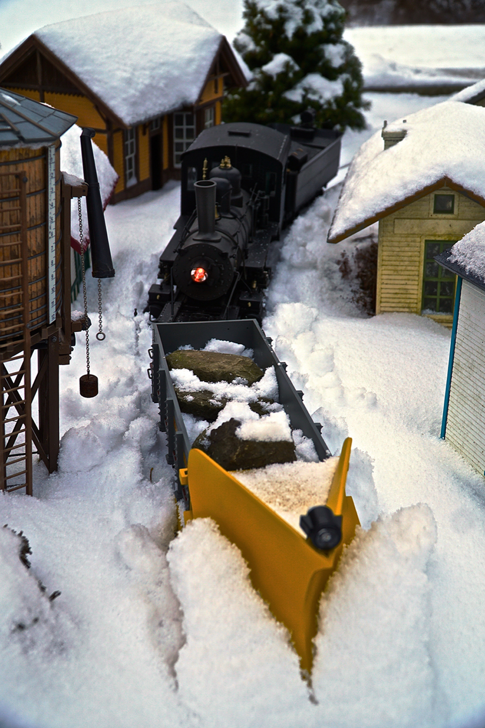 model steam locomotive plows snow with yellow snow plow