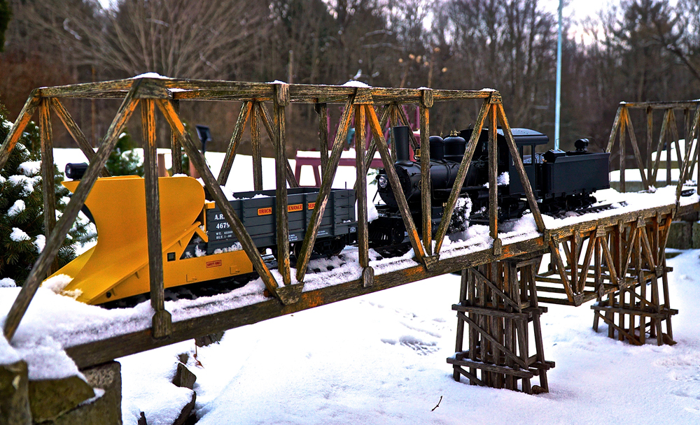 model steam locomotive plows on trestle