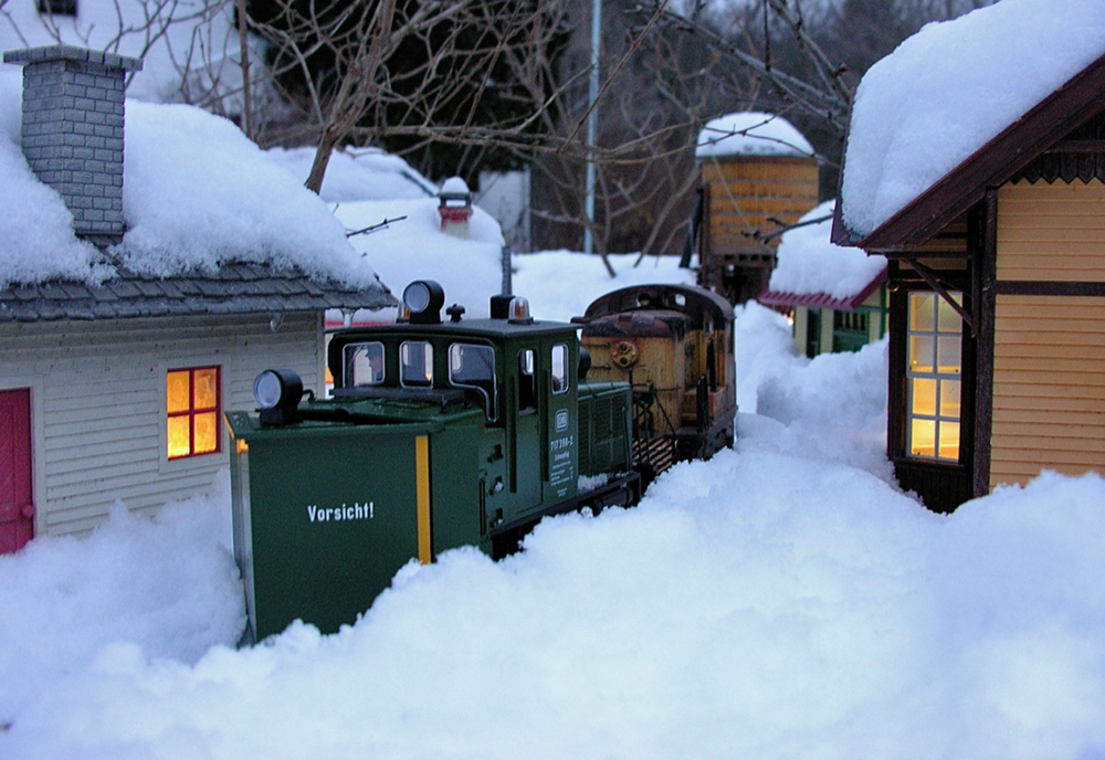 model locomotive with snowplow clearing the tracks on garden railway