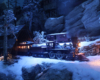 A steam locomotive with a passenger train emerges from a snow shed into a moonlit snowscape